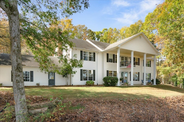 greek revival inspired property with a front lawn and a balcony