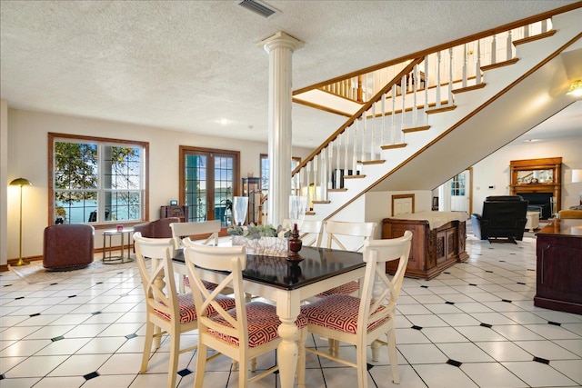 dining area featuring a textured ceiling, ornate columns, and french doors