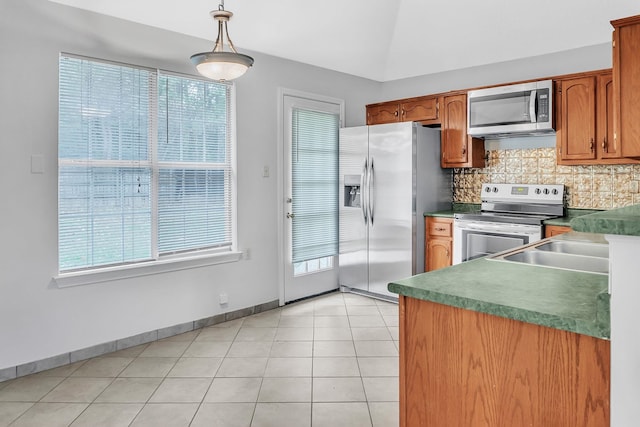 kitchen with stainless steel appliances, hanging light fixtures, sink, light tile patterned flooring, and backsplash