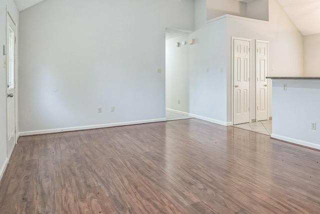 unfurnished living room featuring high vaulted ceiling and light hardwood / wood-style floors