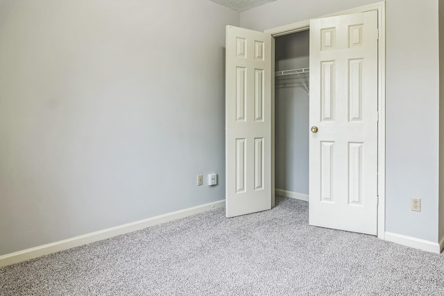 unfurnished bedroom with a closet and light colored carpet