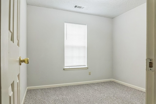 carpeted empty room featuring a textured ceiling