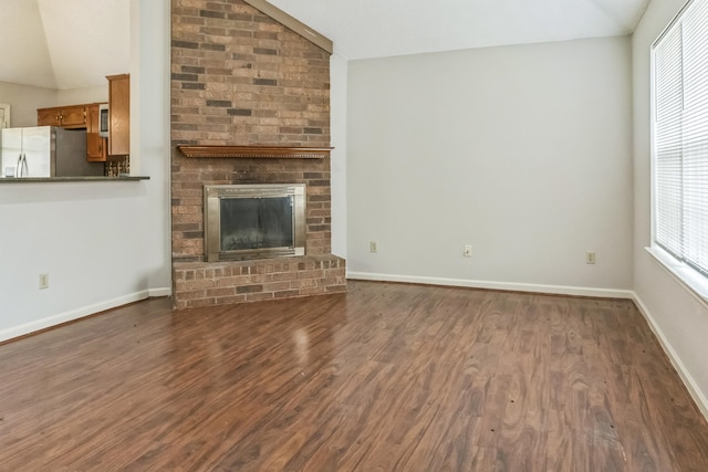 unfurnished living room with a brick fireplace, dark hardwood / wood-style flooring, and vaulted ceiling