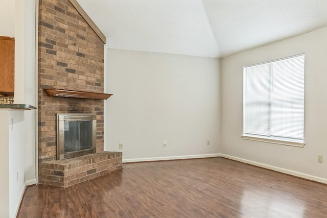 unfurnished living room with a brick fireplace, lofted ceiling, and hardwood / wood-style floors