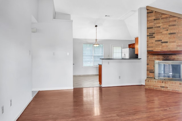 unfurnished living room with a brick fireplace, light wood-type flooring, and high vaulted ceiling