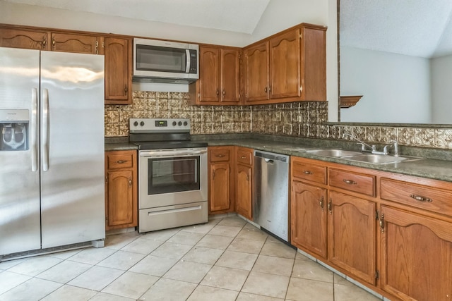 kitchen featuring stainless steel appliances, vaulted ceiling, sink, light tile patterned flooring, and backsplash