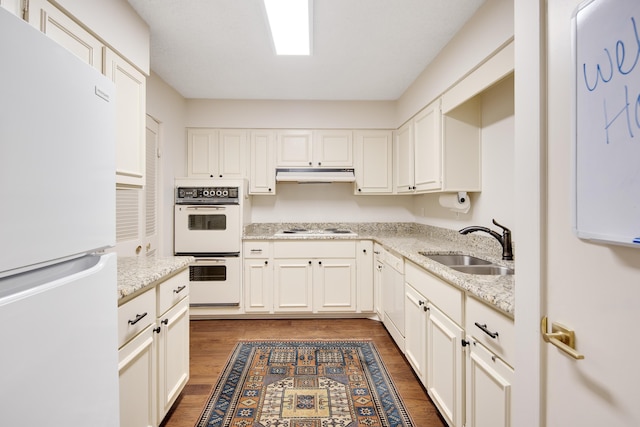 kitchen featuring dark hardwood / wood-style flooring, light stone countertops, sink, white cabinets, and white appliances