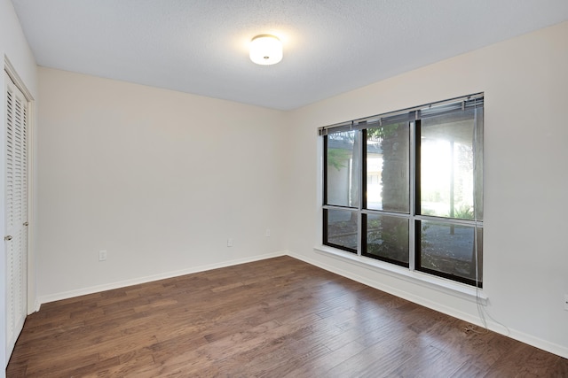 empty room with dark hardwood / wood-style flooring and a textured ceiling