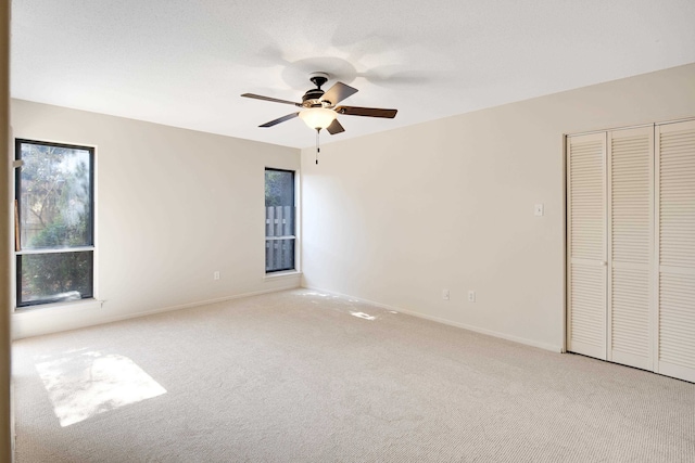 unfurnished bedroom featuring ceiling fan, light carpet, and a closet