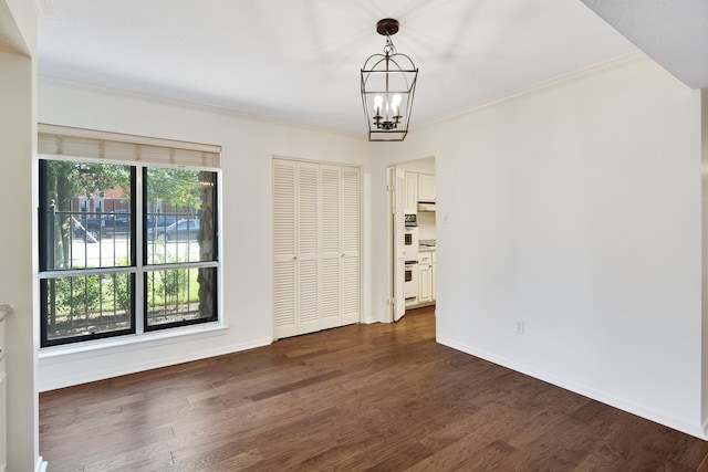 unfurnished room featuring a chandelier, dark hardwood / wood-style floors, and crown molding