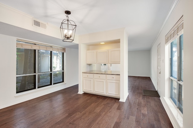 kitchen with ornamental molding, white cabinetry, decorative light fixtures, a notable chandelier, and dark hardwood / wood-style floors