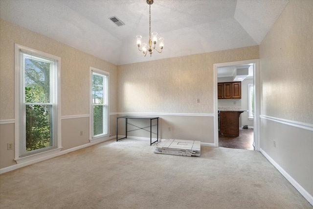 unfurnished room featuring a textured ceiling, an inviting chandelier, vaulted ceiling, and carpet floors