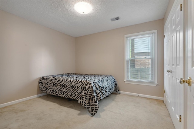 bedroom with light colored carpet and a textured ceiling