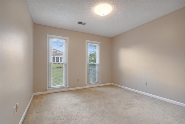 carpeted empty room featuring a textured ceiling