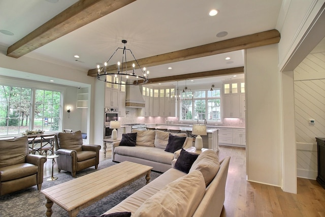 living room with a healthy amount of sunlight, light wood-type flooring, crown molding, and beam ceiling