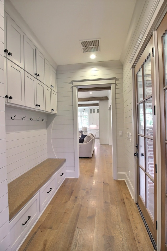 mudroom with light hardwood / wood-style floors and wooden walls