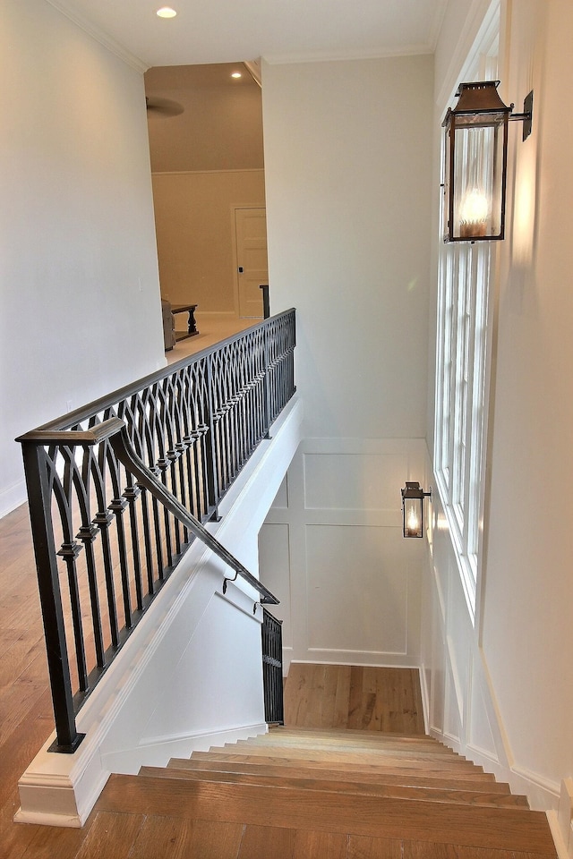 stairway with hardwood / wood-style flooring and ornamental molding