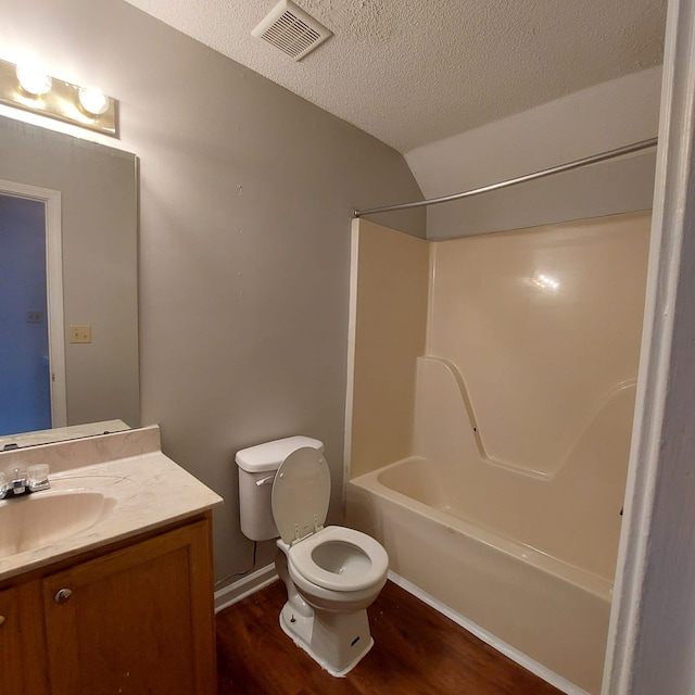 full bathroom featuring vanity, a textured ceiling, hardwood / wood-style flooring, toilet, and lofted ceiling