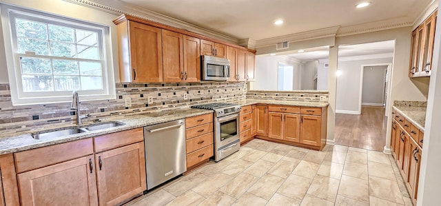 kitchen with sink, light stone counters, appliances with stainless steel finishes, backsplash, and crown molding