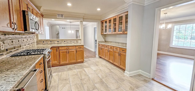 kitchen with stainless steel appliances, light stone counters, and decorative light fixtures