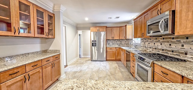 kitchen featuring crown molding, backsplash, light stone countertops, sink, and high quality appliances