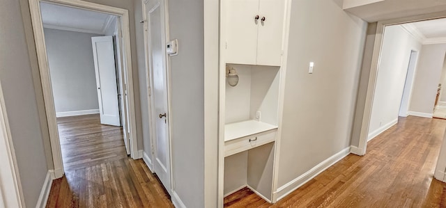 corridor with hardwood / wood-style floors and ornamental molding