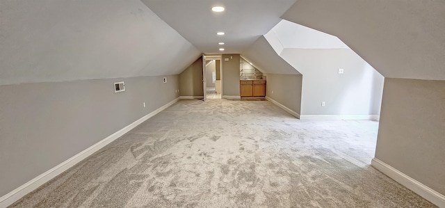 additional living space with light carpet and vaulted ceiling