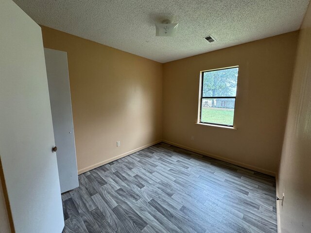 spare room with light hardwood / wood-style floors and a textured ceiling