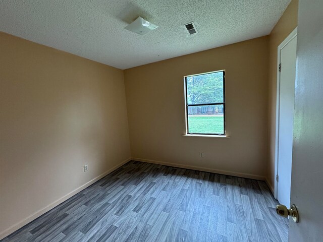 empty room with a textured ceiling and light hardwood / wood-style floors