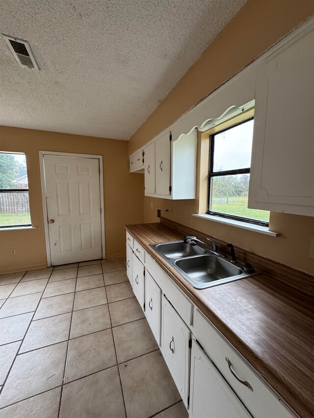 kitchen with white cabinets, a wealth of natural light, sink, and light tile patterned flooring