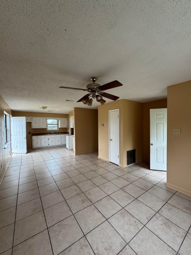 tiled spare room with a textured ceiling and ceiling fan