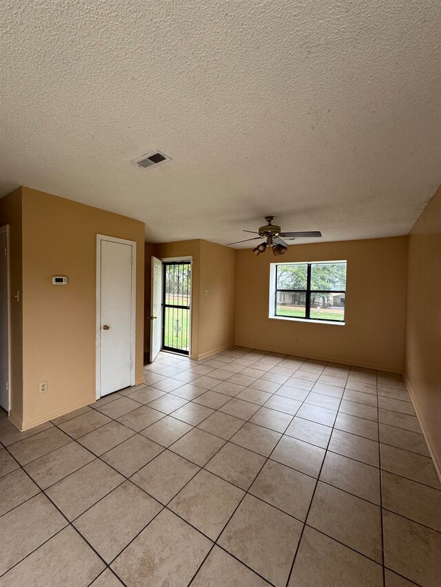 tiled spare room featuring a textured ceiling, a healthy amount of sunlight, and ceiling fan