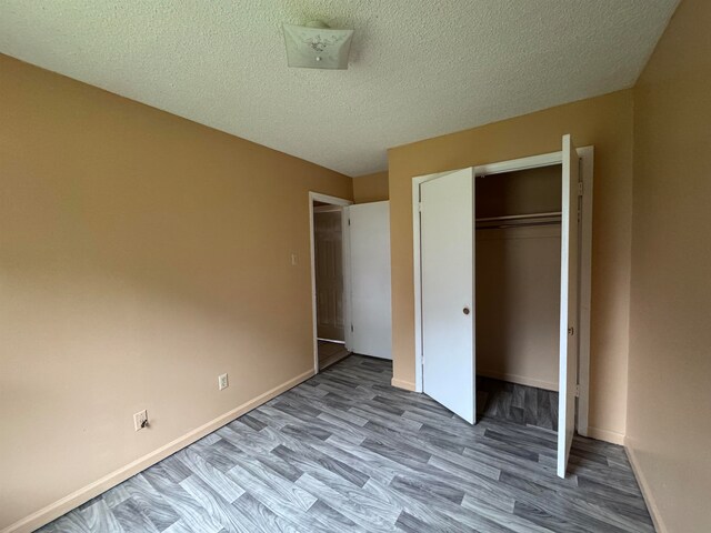 unfurnished bedroom with light wood-type flooring, a textured ceiling, and a closet