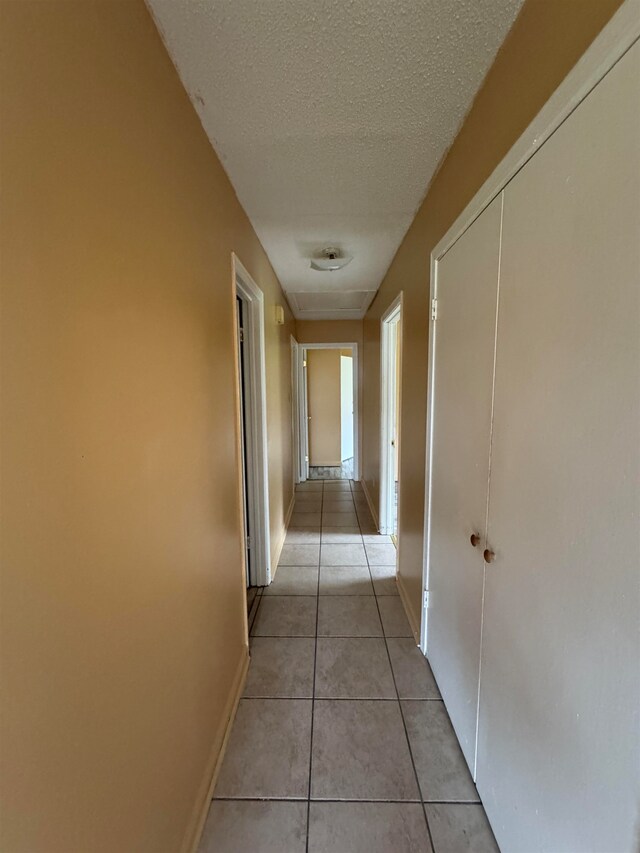 hall with light tile patterned flooring and a textured ceiling