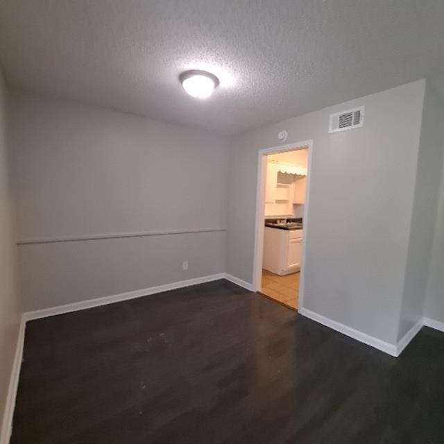 empty room featuring dark hardwood / wood-style flooring and a textured ceiling