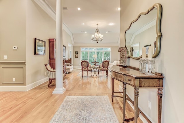 hallway featuring a chandelier, ornamental molding, light wood-type flooring, and decorative columns