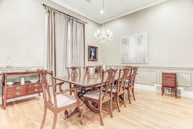 dining room featuring a chandelier, light hardwood / wood-style flooring, and ornamental molding