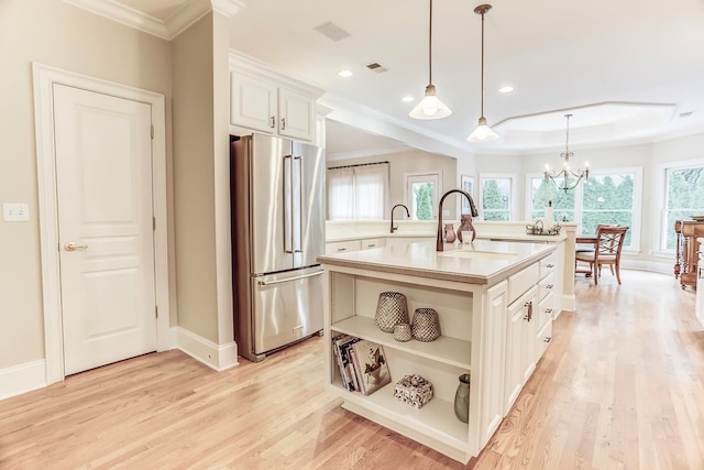 kitchen with high end refrigerator, white cabinetry, a kitchen island with sink, light hardwood / wood-style flooring, and pendant lighting