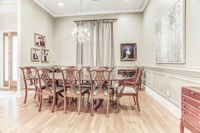 dining room with ornamental molding, light hardwood / wood-style flooring, and an inviting chandelier