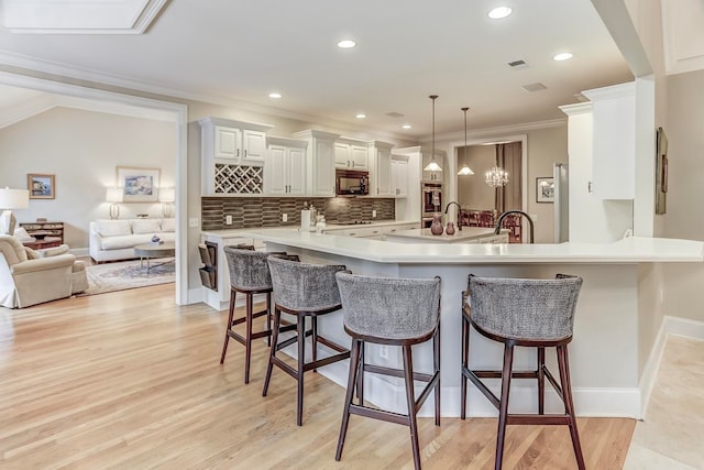 kitchen with light wood-type flooring, kitchen peninsula, decorative backsplash, and a breakfast bar area