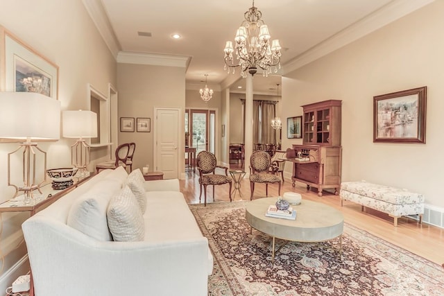 living room featuring an inviting chandelier, crown molding, and light hardwood / wood-style flooring