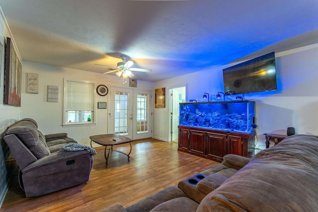 living room featuring ceiling fan, wood-type flooring, a textured ceiling, and french doors