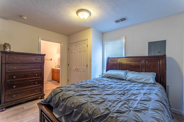 bedroom featuring connected bathroom, a closet, a textured ceiling, and light hardwood / wood-style floors