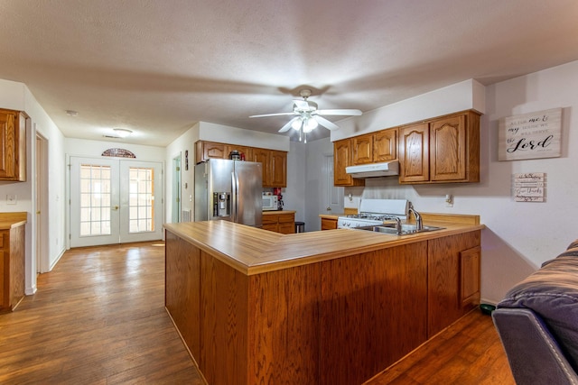 kitchen with hardwood / wood-style flooring, stainless steel refrigerator with ice dispenser, kitchen peninsula, and white gas range oven