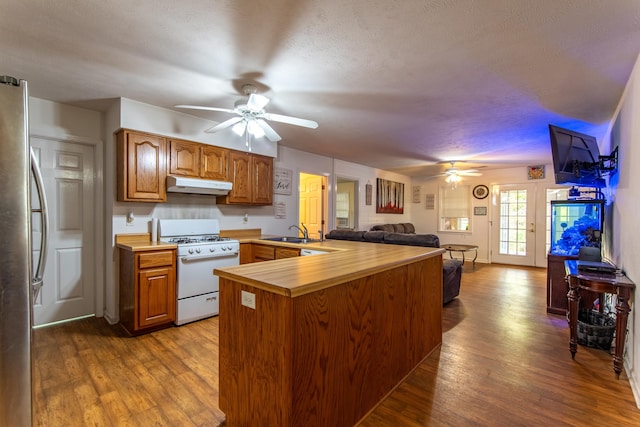 kitchen featuring white gas range oven, stainless steel refrigerator, dark hardwood / wood-style floors, sink, and kitchen peninsula