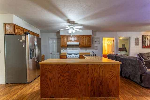 kitchen featuring white range with gas stovetop, wood-type flooring, a center island with sink, and stainless steel fridge with ice dispenser