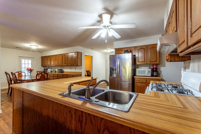 kitchen featuring ventilation hood, wood-type flooring, sink, white appliances, and ceiling fan