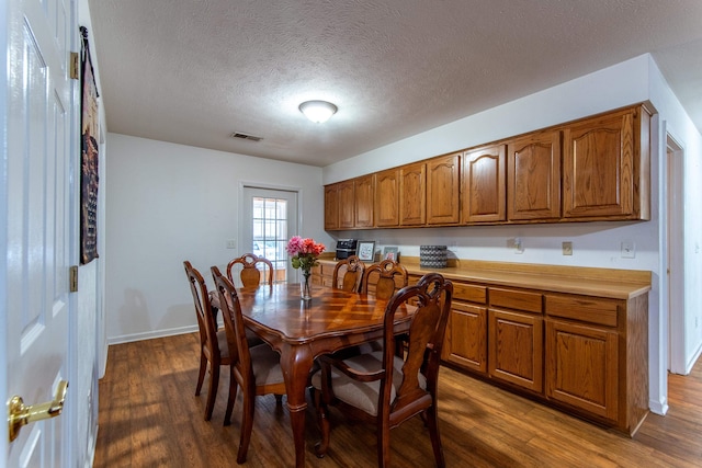 dining area with a textured ceiling and dark hardwood / wood-style flooring