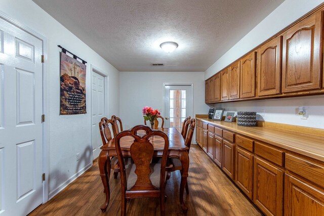 dining room with dark hardwood / wood-style floors and a textured ceiling