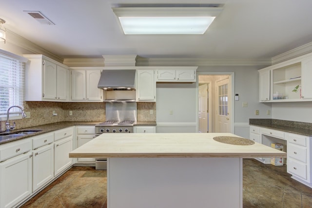 kitchen featuring ornamental molding, tasteful backsplash, sink, and wall chimney range hood